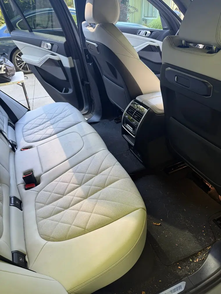 Grey BMW X5 rear seats and floor with leaves and debris before a mobile interior detail by A&F Auto Detailing in Oakland Township, MI