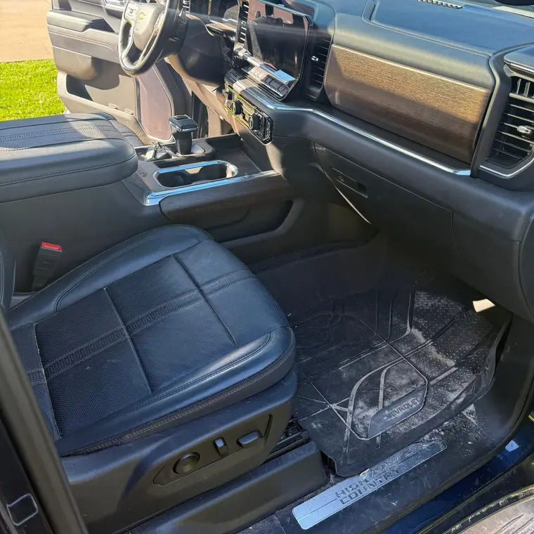 Dark blue Chevrolet Silverado High Country passenger footwell with a dirty floor mat before a mobile interior detail by A&F Auto Detailing in Rochester Hills, MI