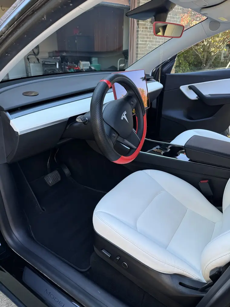 Clean white driver seat and floor mat in a black Tesla Model Y after a mobile interior detail by A&F Auto Detailing in Richmond, MI