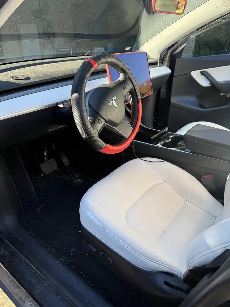Black Tesla Model Y driver seat and dusty floor before a mobile interior detail by A&F Auto Detailing in Richmond, MI